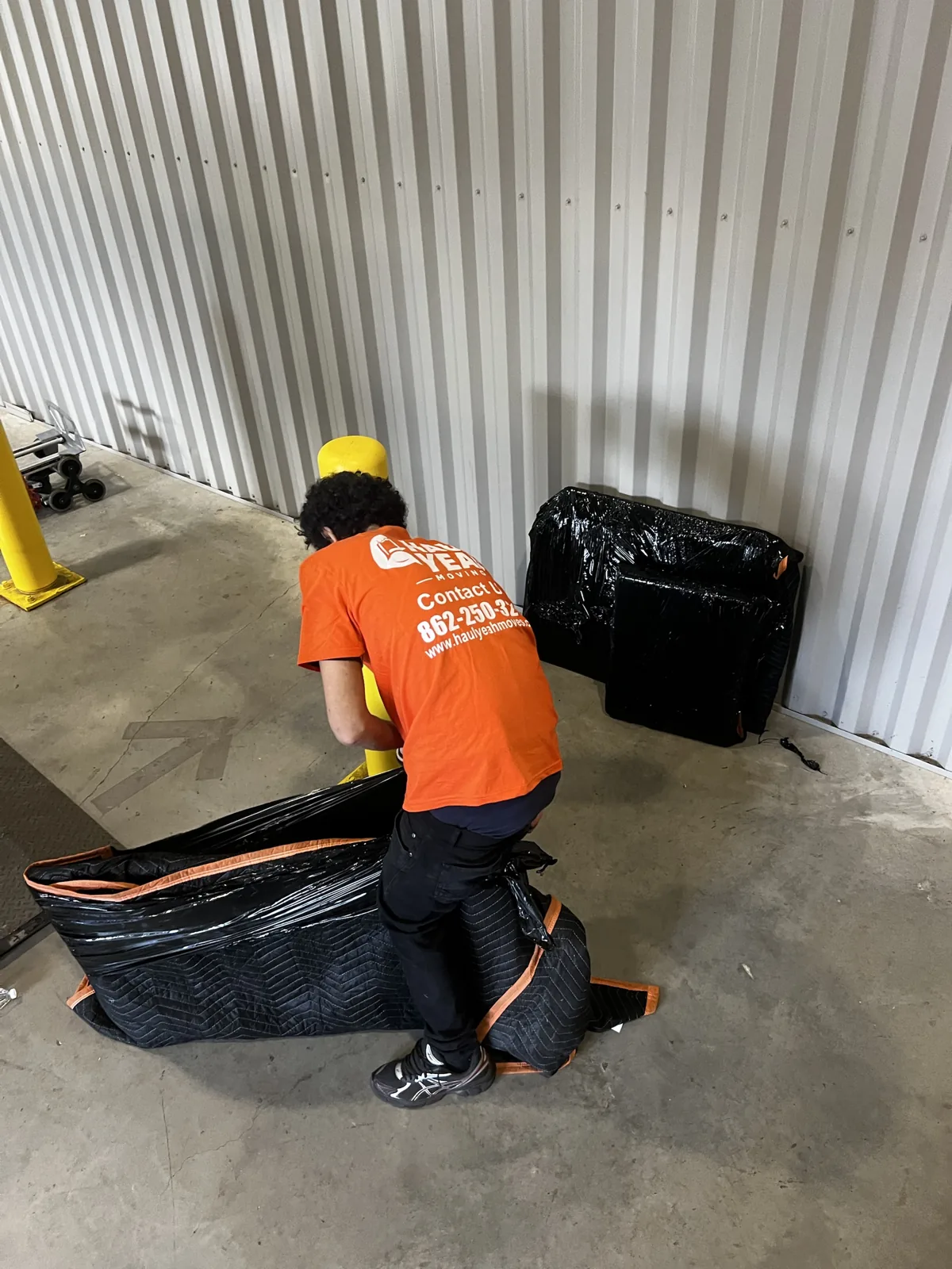 A Haul Yeah mover shrink-wrapping and blanket-padding furniture before a New Jersey move
