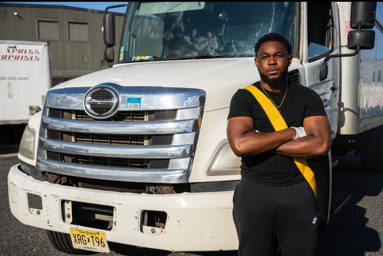 Haul Yeah mover standing arms-crossed in front of a New Jersey-plated 26-ft moving truck in Essex County